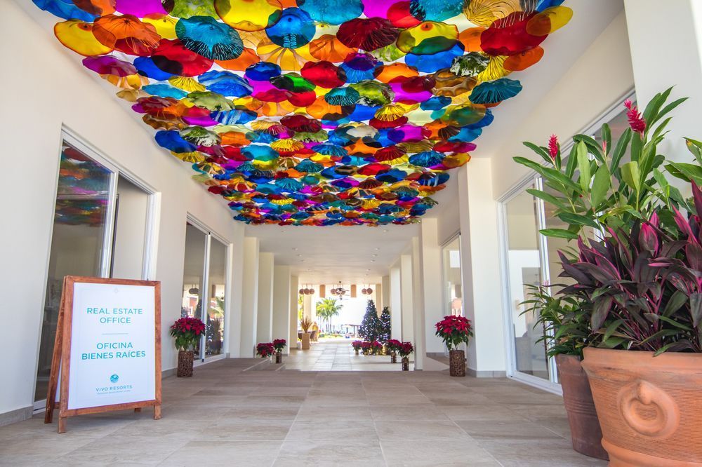 Hallway with a colorful, decorative ceiling and potted plants; sign for fitness office.
