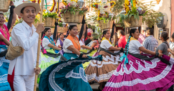 Dancers in colorful traditional dress perform a festive street dance during a cultural parade