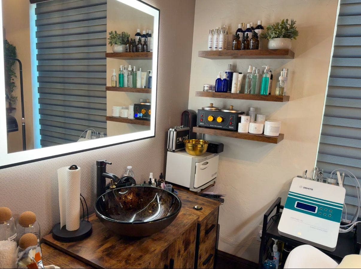 A bathroom with a sink , mirror , shelves and a machine.