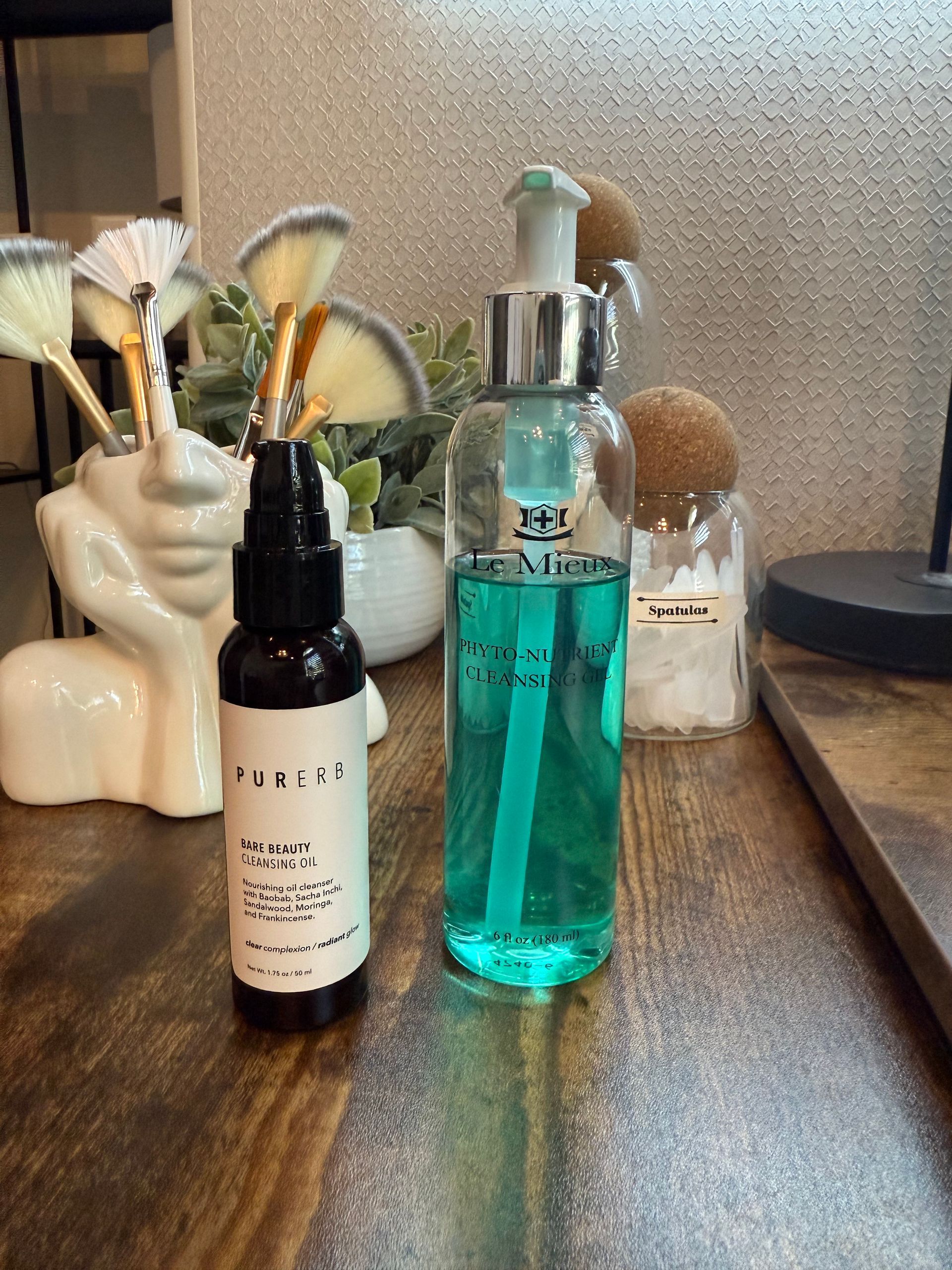 Two bottles of liquid are sitting on a wooden table.