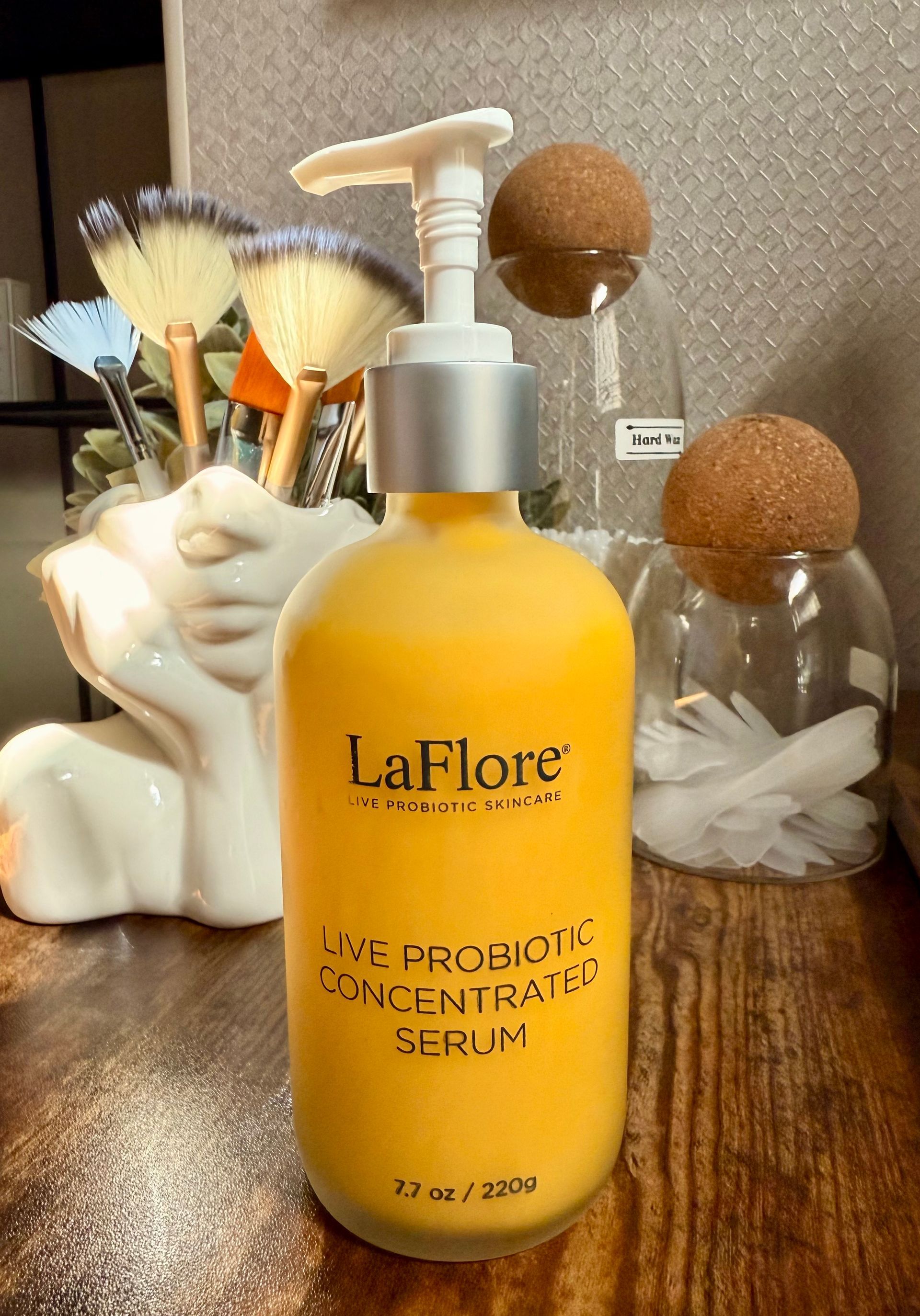 A bottle of la flore concentrated serum is sitting on a wooden table.