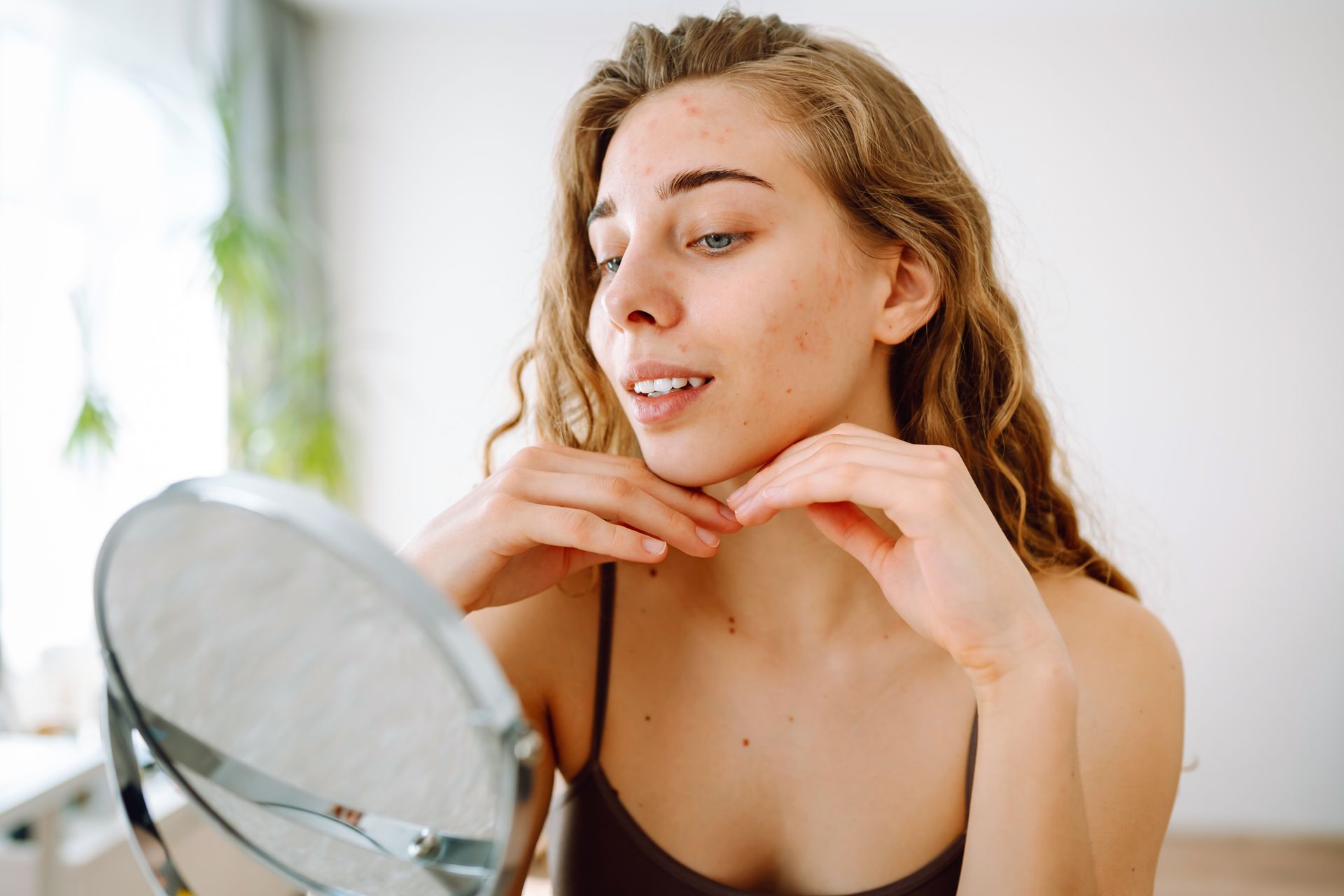Woman applying skincare near a mirror in a bright bathroom