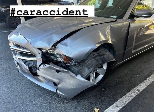 A car with a damaged front end is parked in a parking lot.