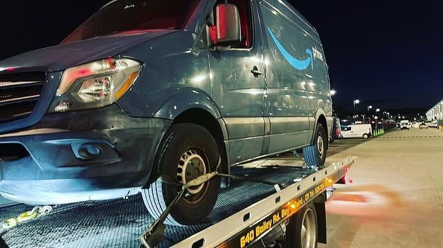 Delivery van loaded on an AT Towing flatbed at night