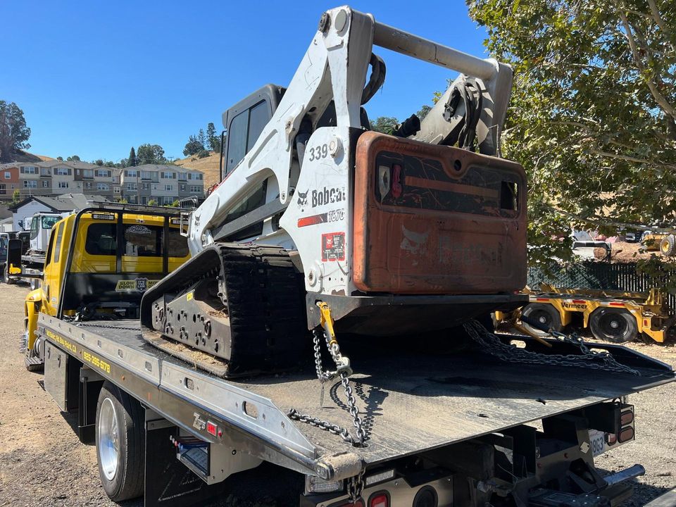 Tracked skid steer chained down on an AT Towing flatbed