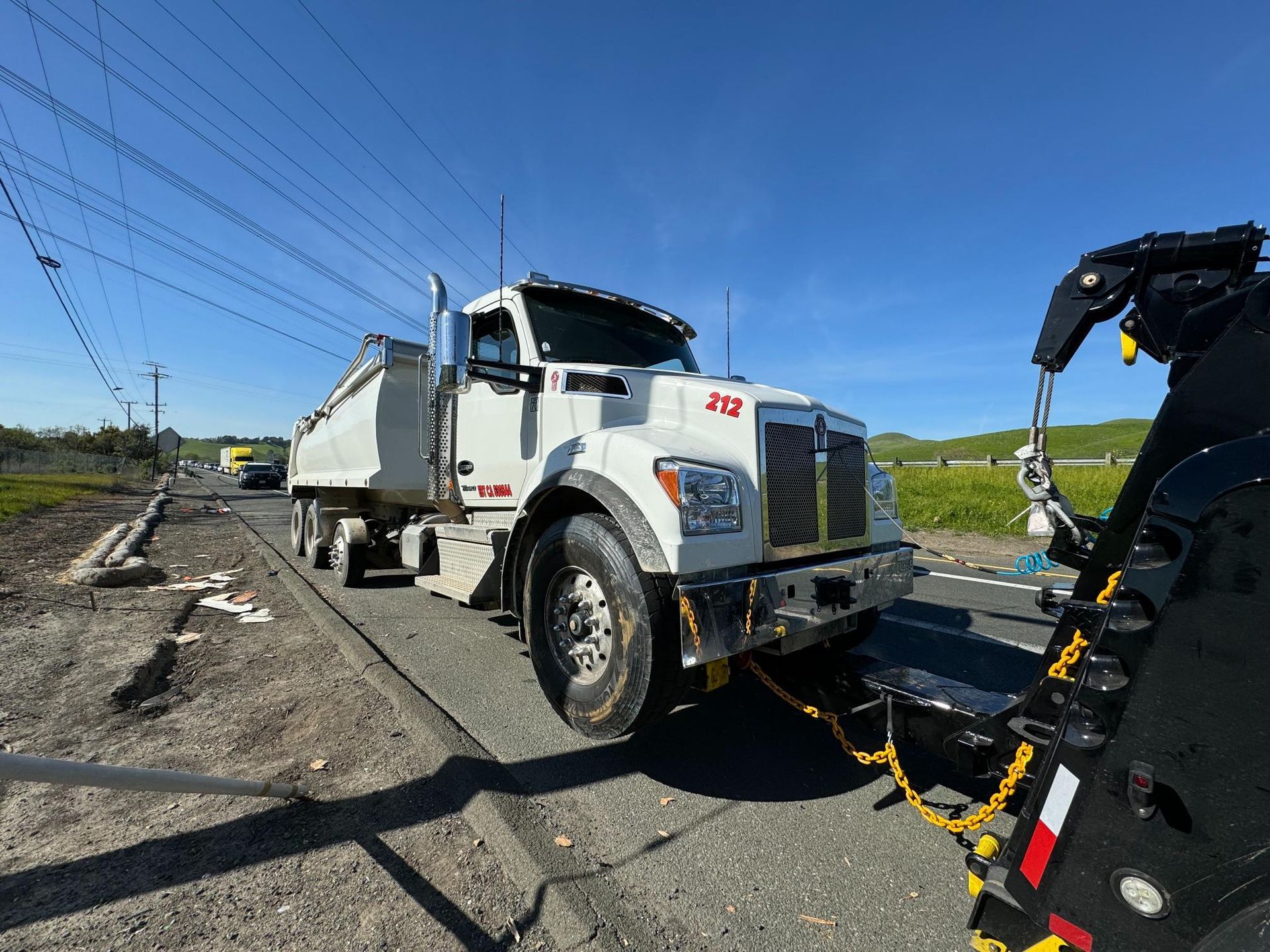 A tow truck is towing a semi truck in a parking lot.
