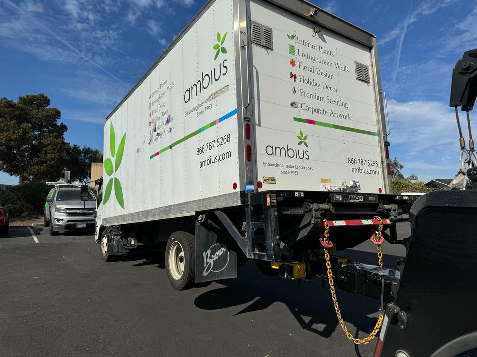 Box truck hooked to an AT Towing wrecker in a parking lot