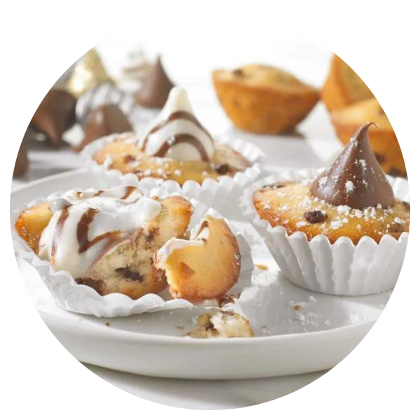 A white plate topped with cupcakes with chocolate kisses on top