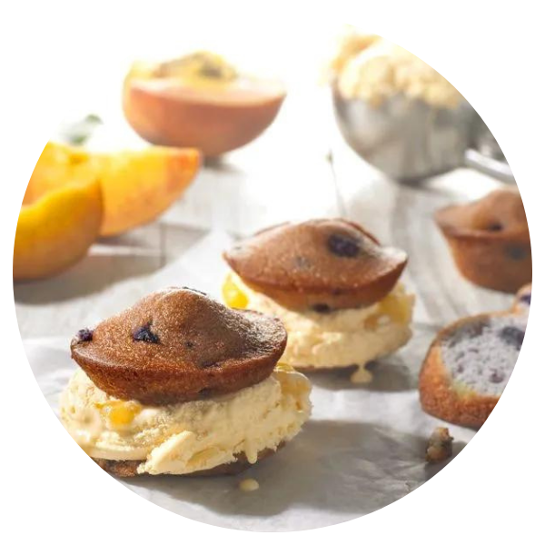 A bunch of cupcakes on a table with fruit in the background