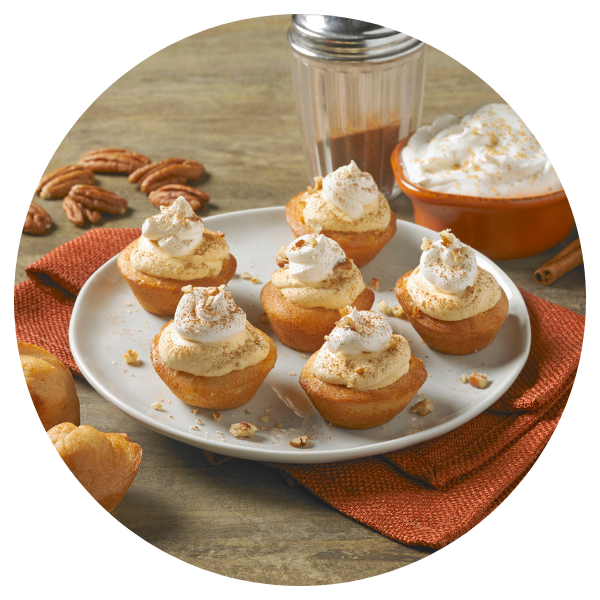 A white plate topped with cupcakes with whipped cream on top