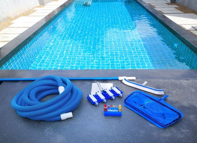 Pool cleaning supplies arranged beside a clear blue swimming pool