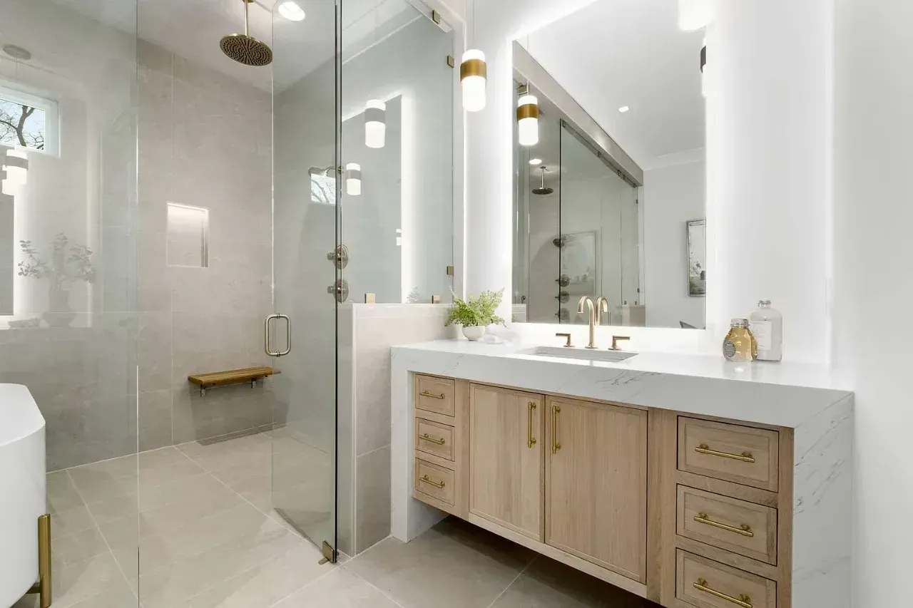 Modern bathroom with glass shower, large mirror, and light wood vanity with marble countertop