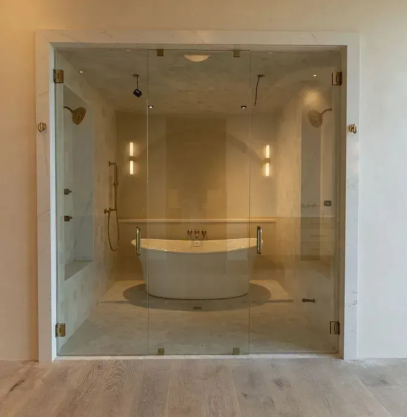 Glass-enclosed modern bathroom with a freestanding oval tub and warm wall lights