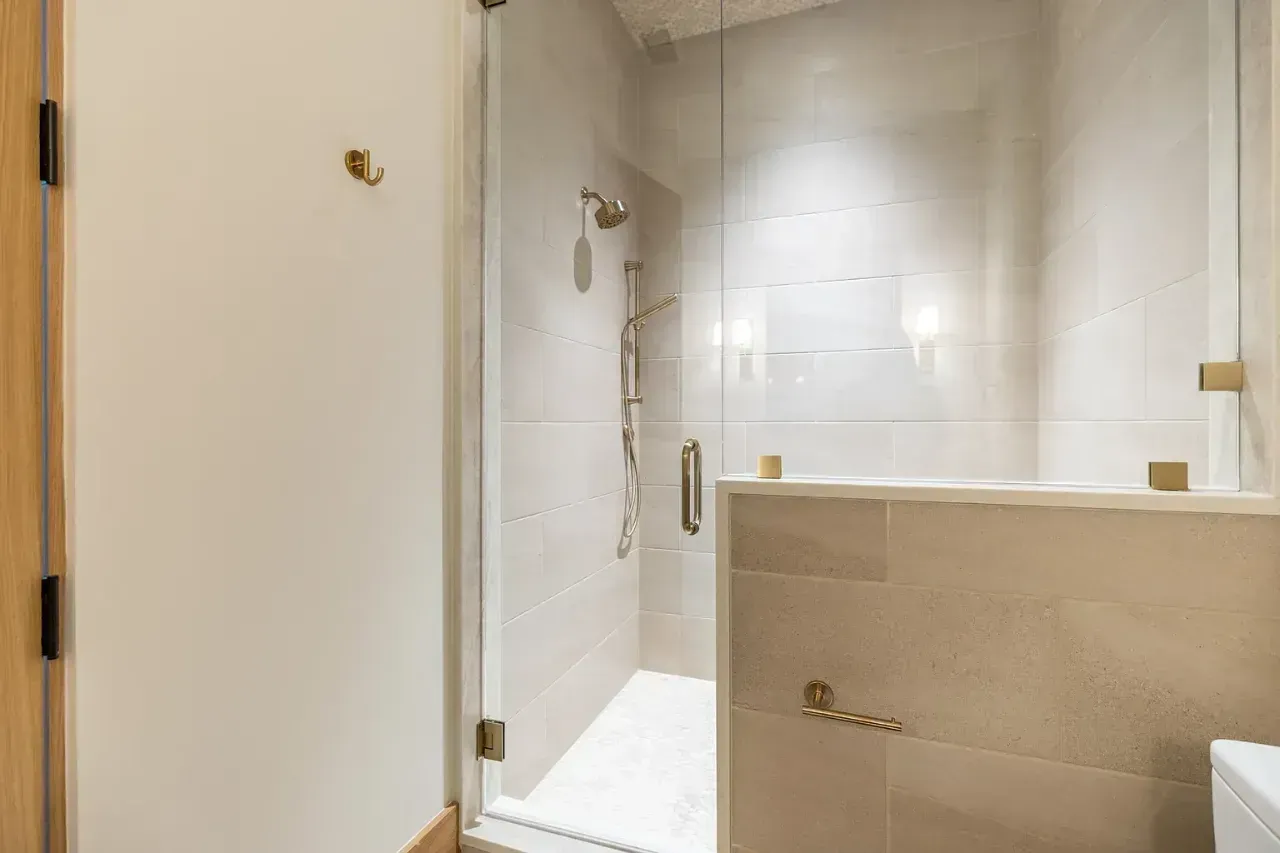 Modern beige-tiled bathroom with a glass shower enclosure and chrome fixtures