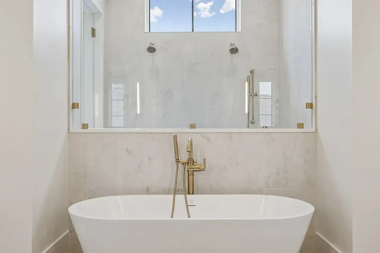 Modern bathroom with a freestanding bathtub, gold fixtures, and a large mirror above it