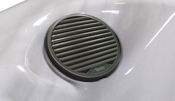 Close-up of a gray speaker grille embedded in the white interior of a hot tub.