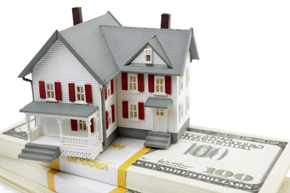 Model house atop stacks of hundred dollar bills.