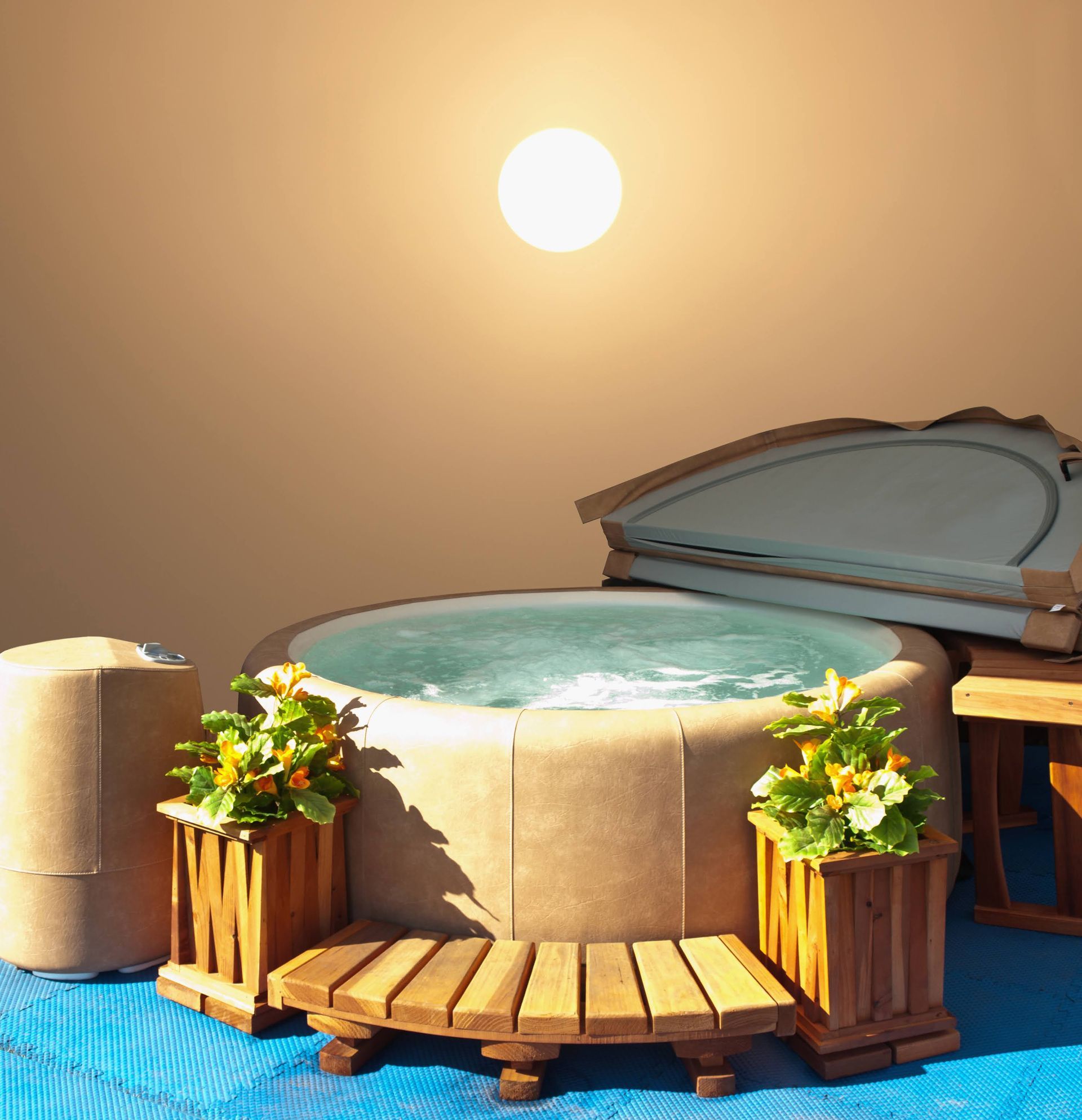 Hot tub with open cover, wooden planters, and setting sun.