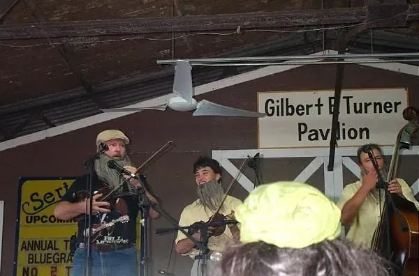 A group of men are playing instruments in front of a sign that says gilbert turner pavilion