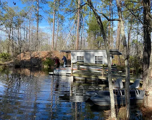 A boat is docked in front of a house in the middle of a lake.
