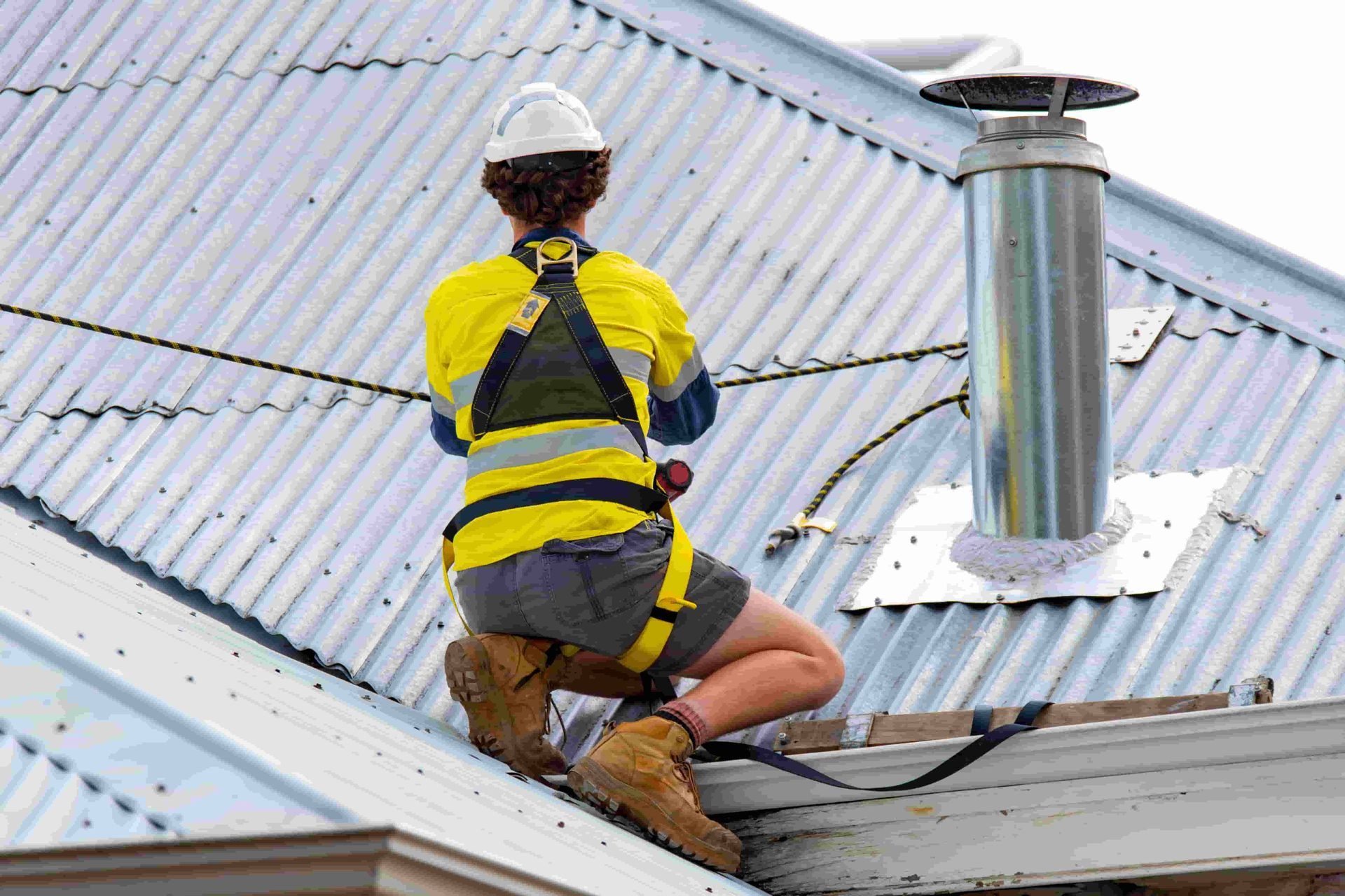A Man is Sitting on Metal Roof — Woodger's Metal Roofing Specialists Pty Ltd in South West Rocks, NSW