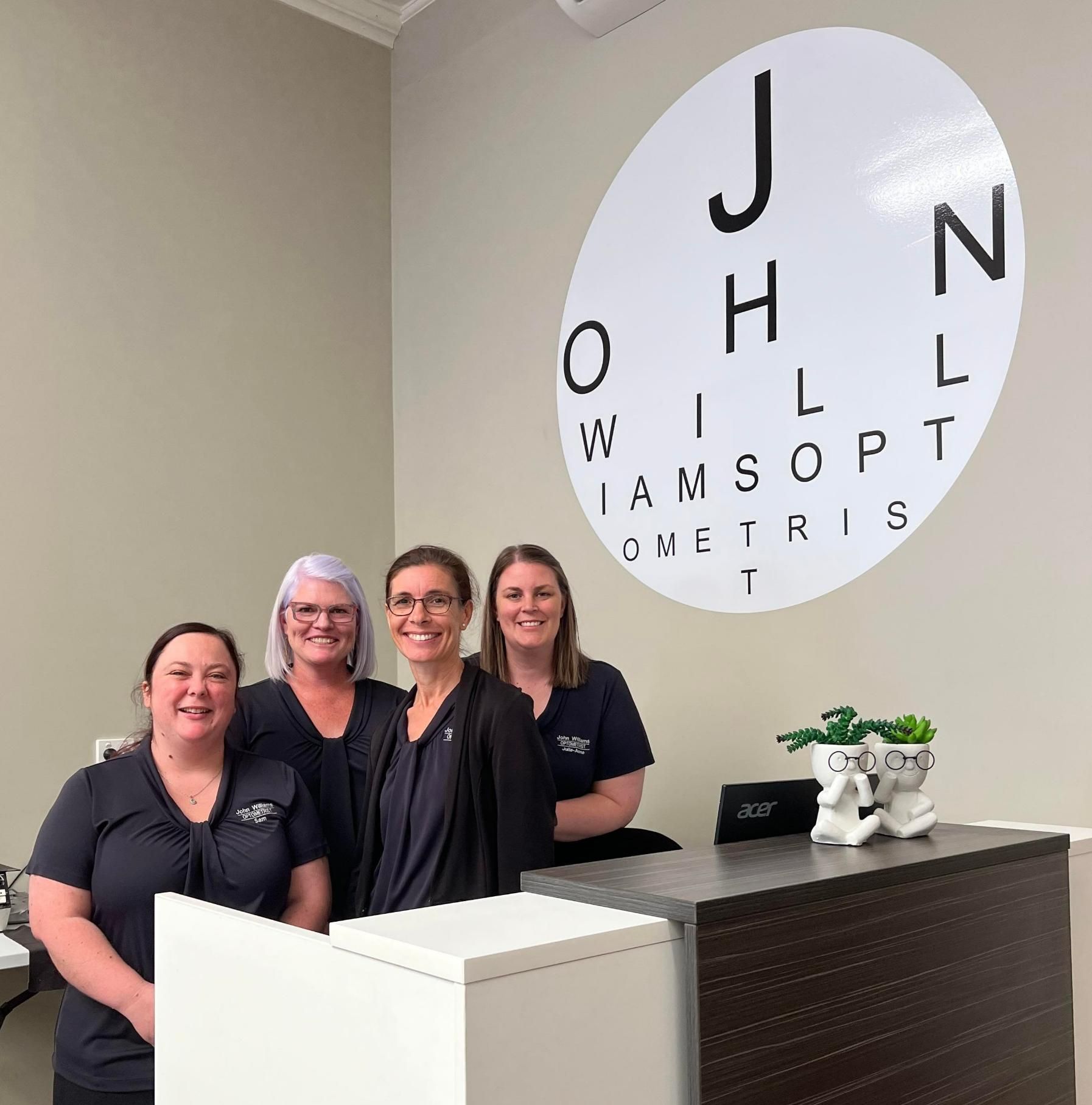A Group of Women Standing in Front of A Sign — John Williams Optometrist in Grafton, NSW
