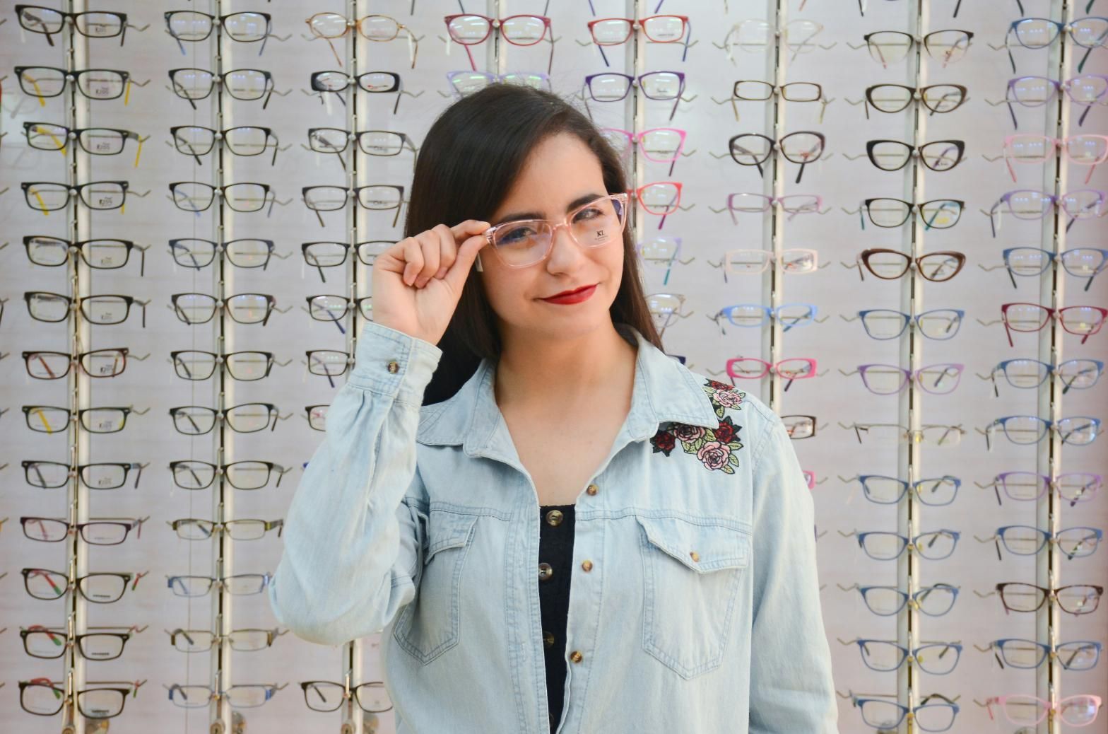 A Woman Is Wearing Glasses in Front of A Wall of Glasses  — John Williams Optometrist in Grafton, NSW 