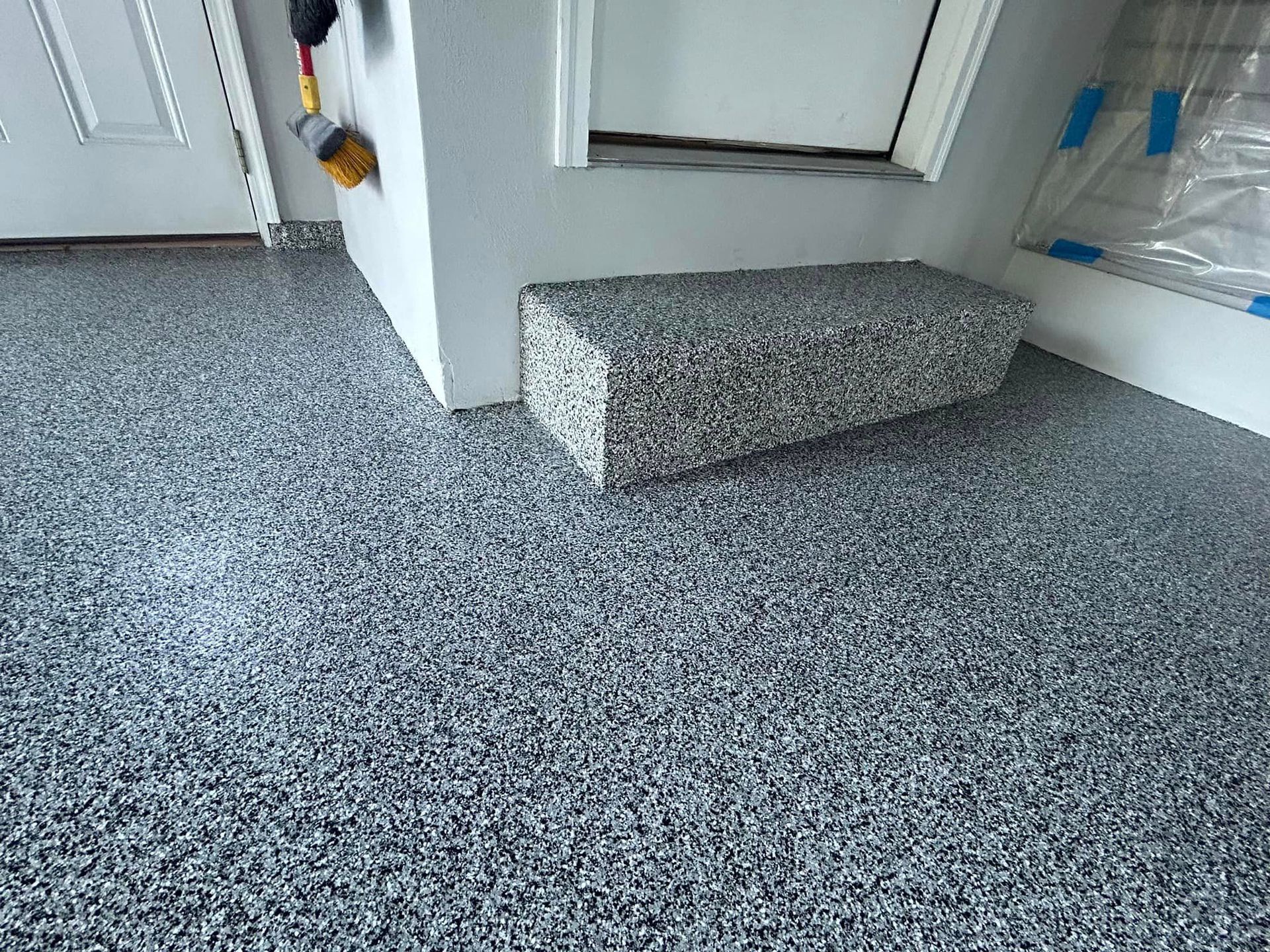 A room with a gray floor and stairs leading up to a door.