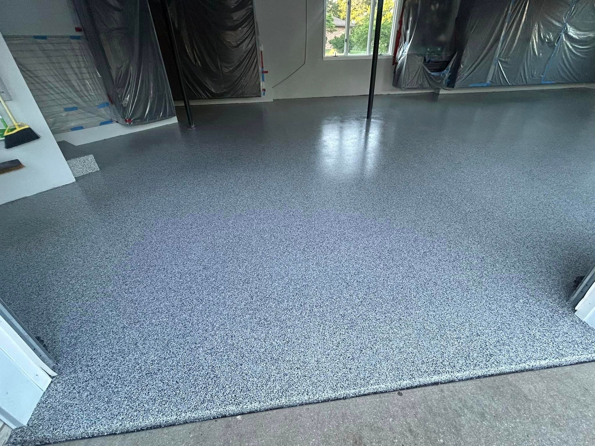 A garage with a gray concrete floor and a window.