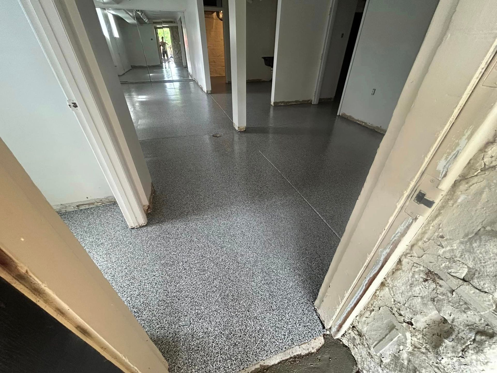 A hallway in a house with a gray floor and white walls.