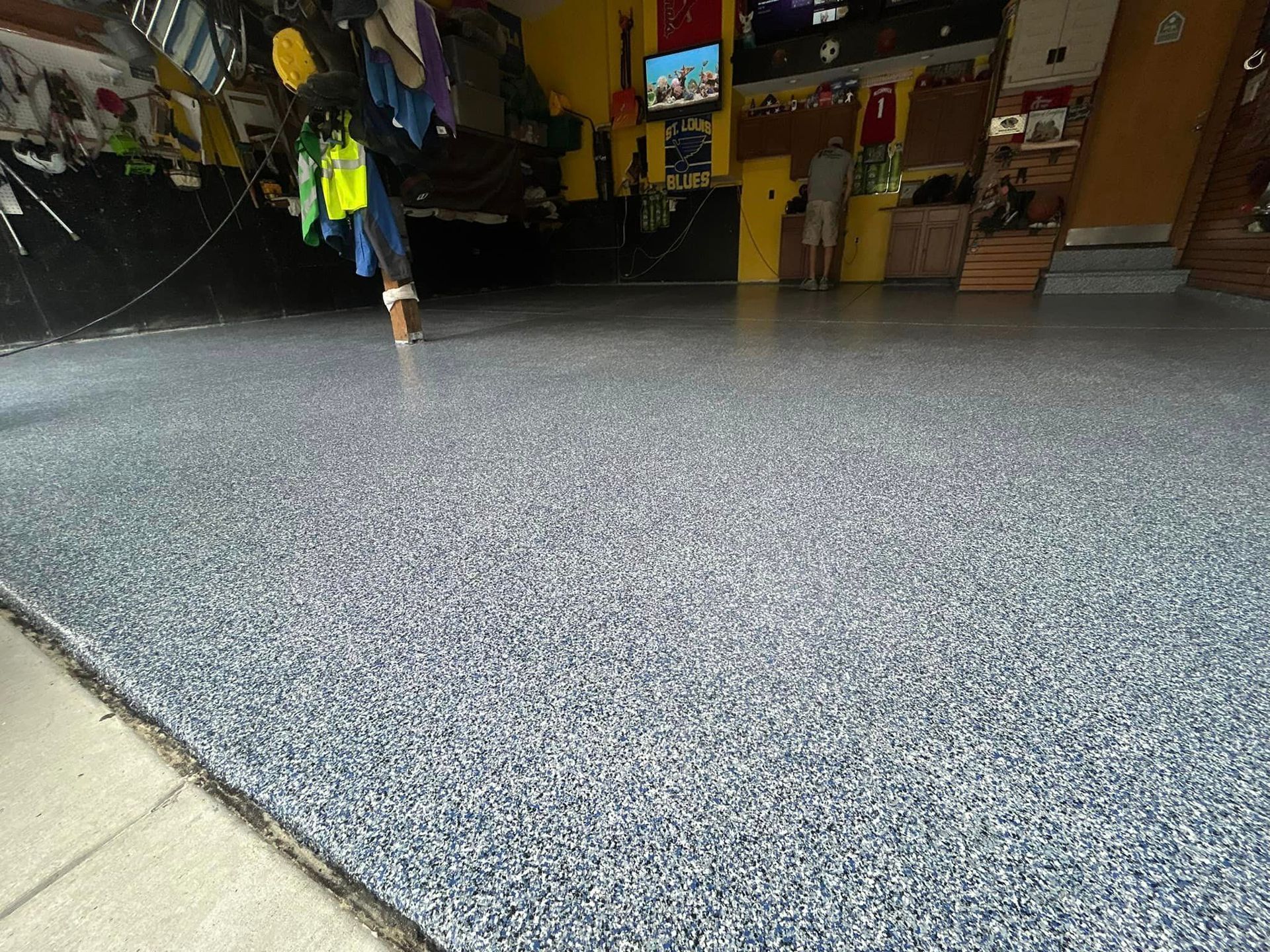 A person is walking on a gray carpeted floor in a garage.