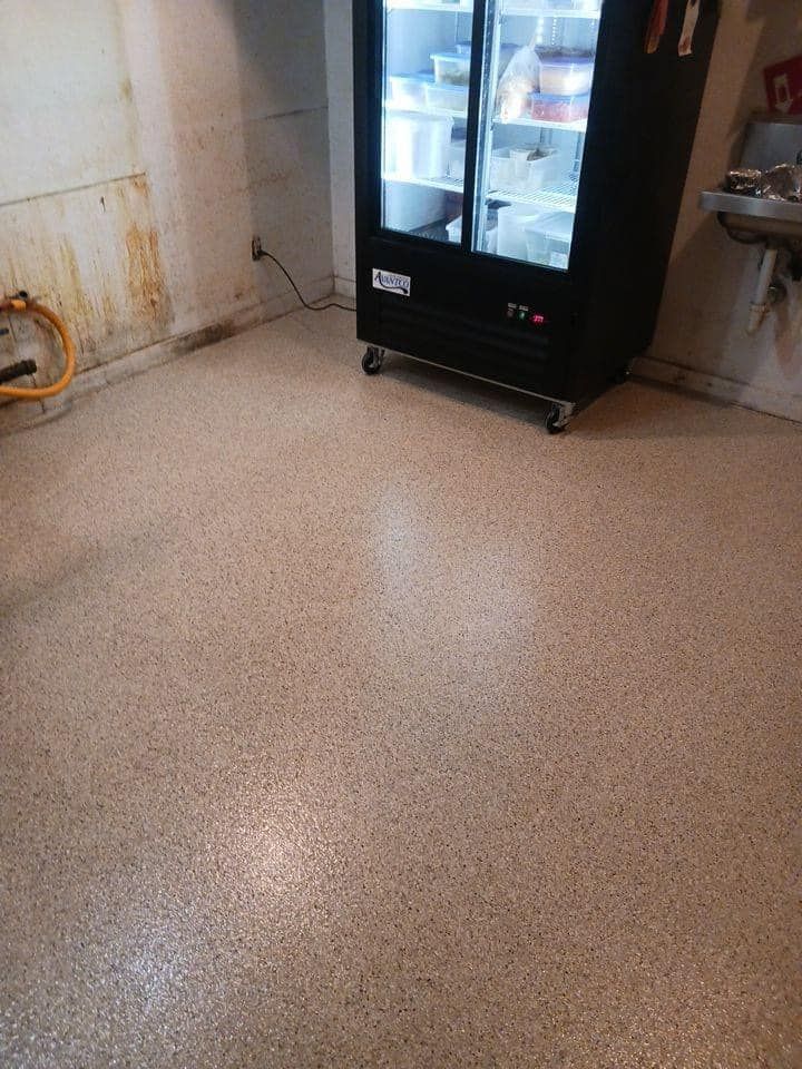 A room with a refrigerator and a hose on the floor.