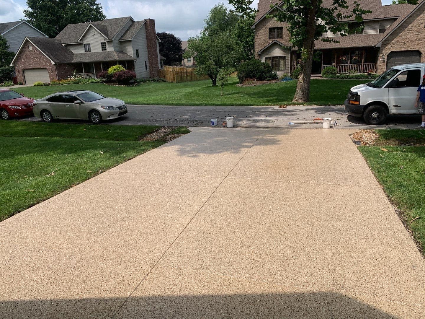 A concrete driveway is being painted in a residential neighborhood.