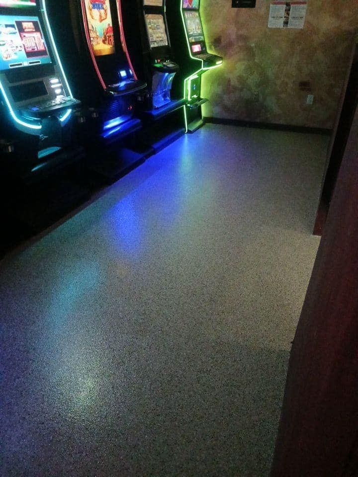 A room with a lot of arcade games and a blue light on the floor.