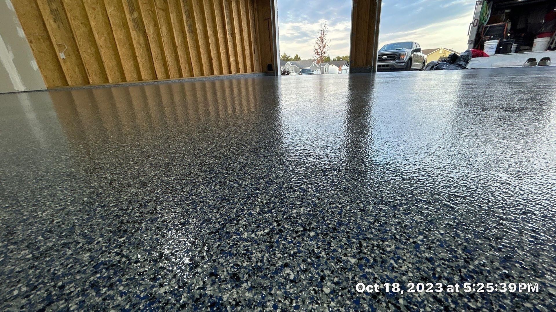 A close up of a shiny concrete floor with a car parked in the background.