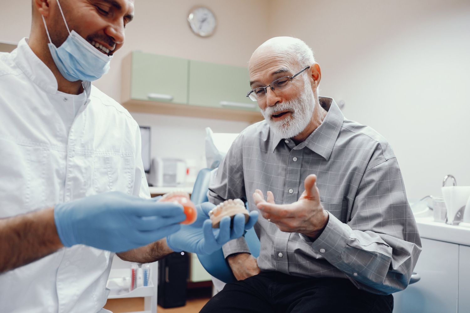 Dental professional fitting a blue glove on a smiling patient in a clinic room