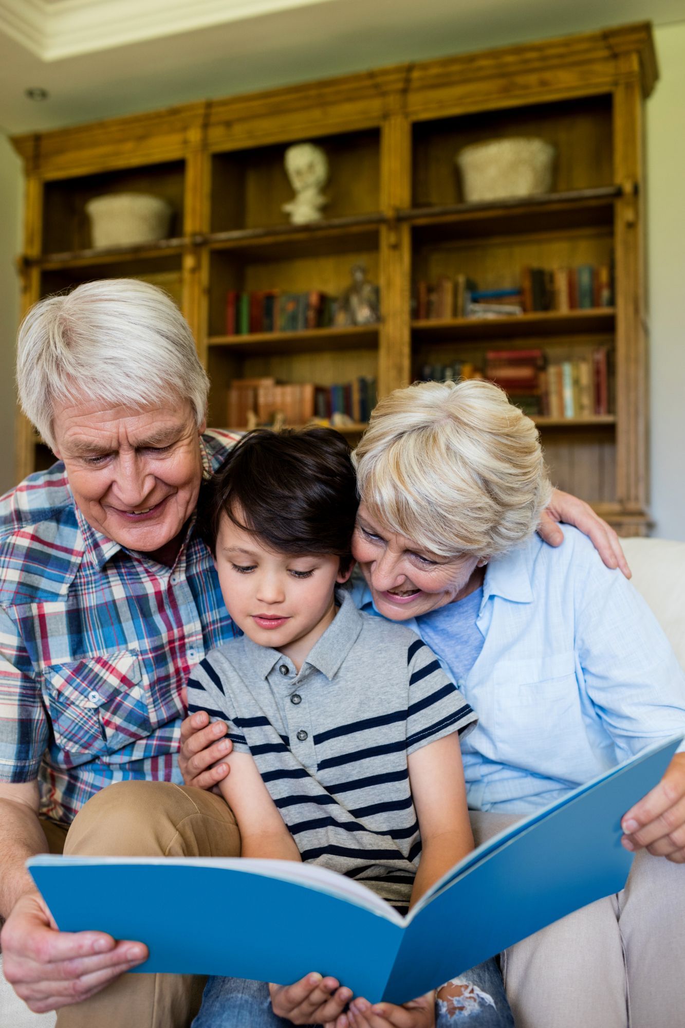 Three people reading a blue book together in a cozy library room