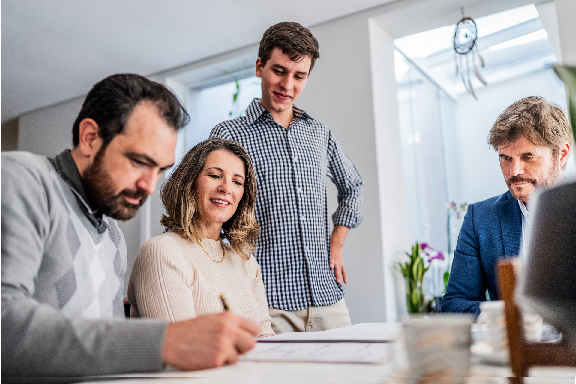 Four people collaborating at a desk in a bright office, reviewing documents together.