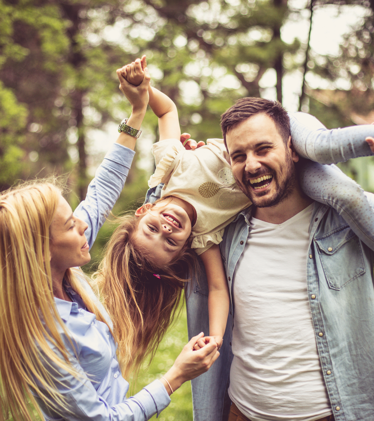 Friends laughing and playing outdoors in a park, with one person being lifted onto another’s shoulders.
