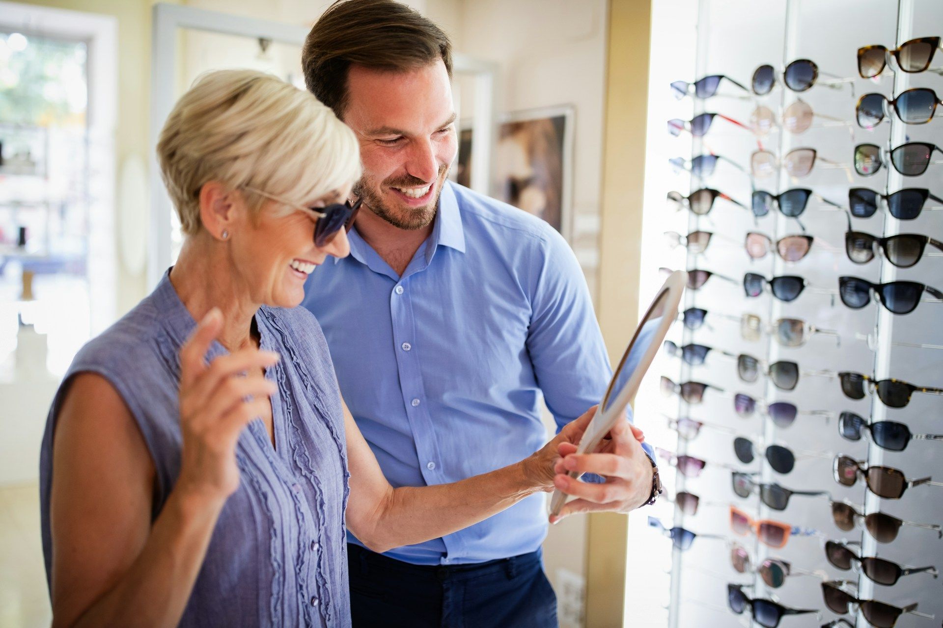 Two people comparing eyeglass frames in a bright optical store