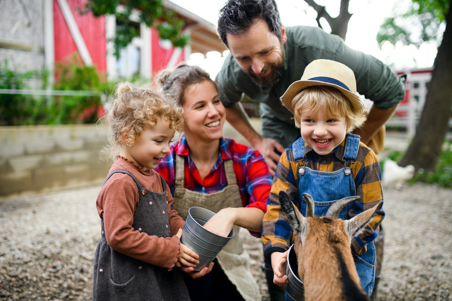 Family smiling while petting a pony outdoors on a farm path