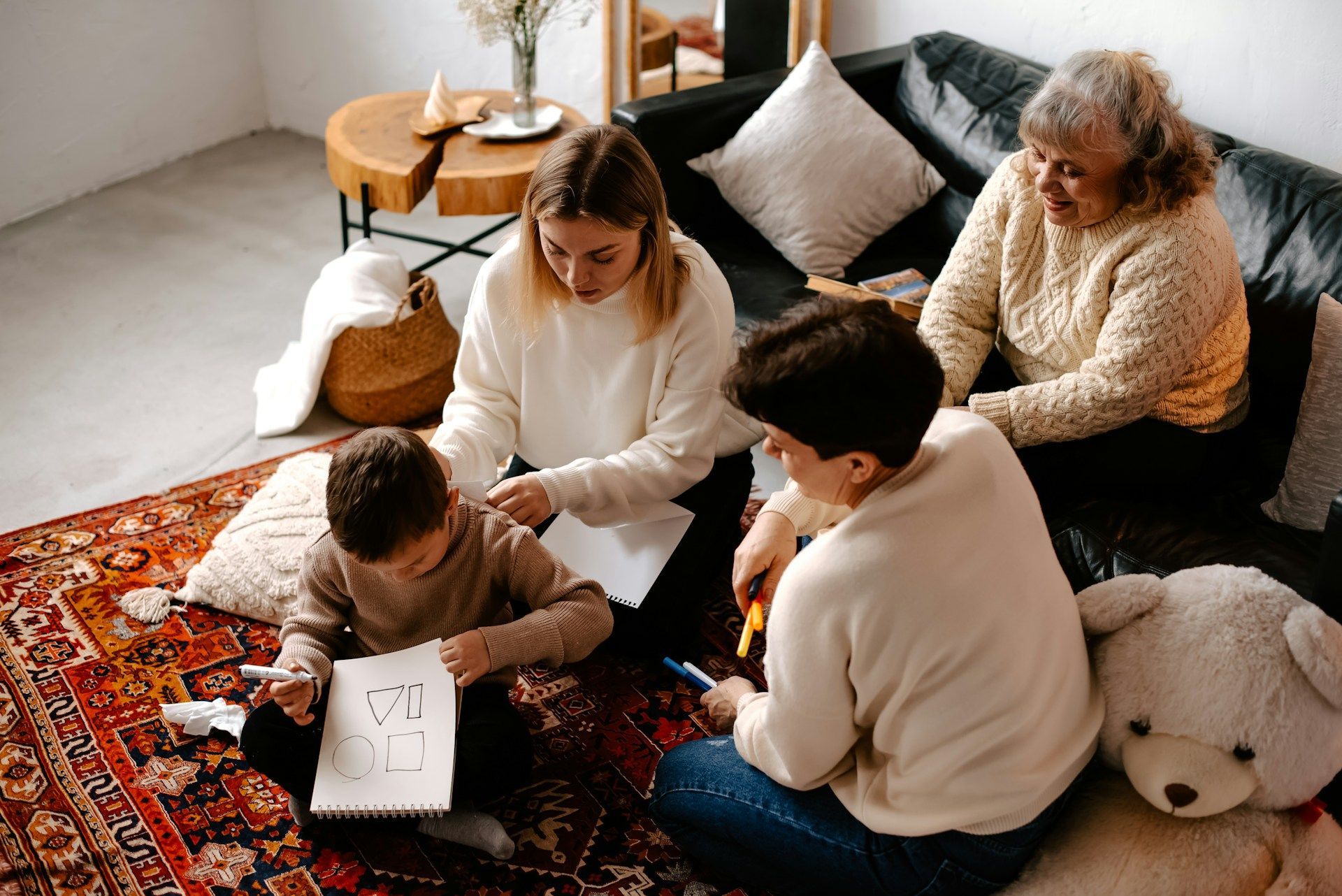 Family gathered on a rug, reading and drawing together in a cozy living room.