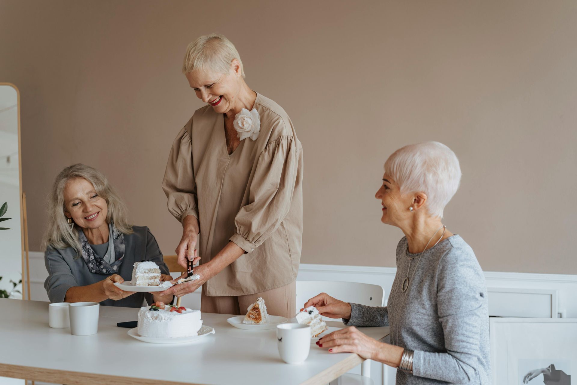 Three people chatting and sharing tea at a bright table in a cozy room