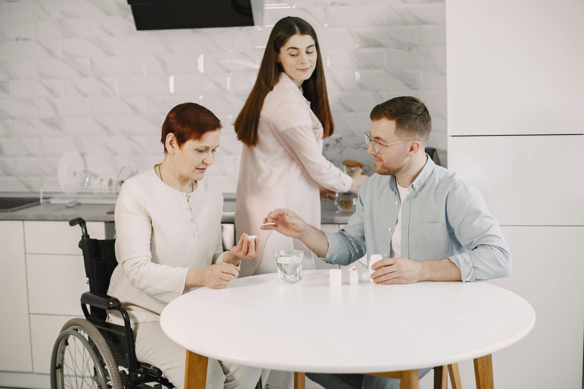 Three people in a bright office discuss documents around a round table