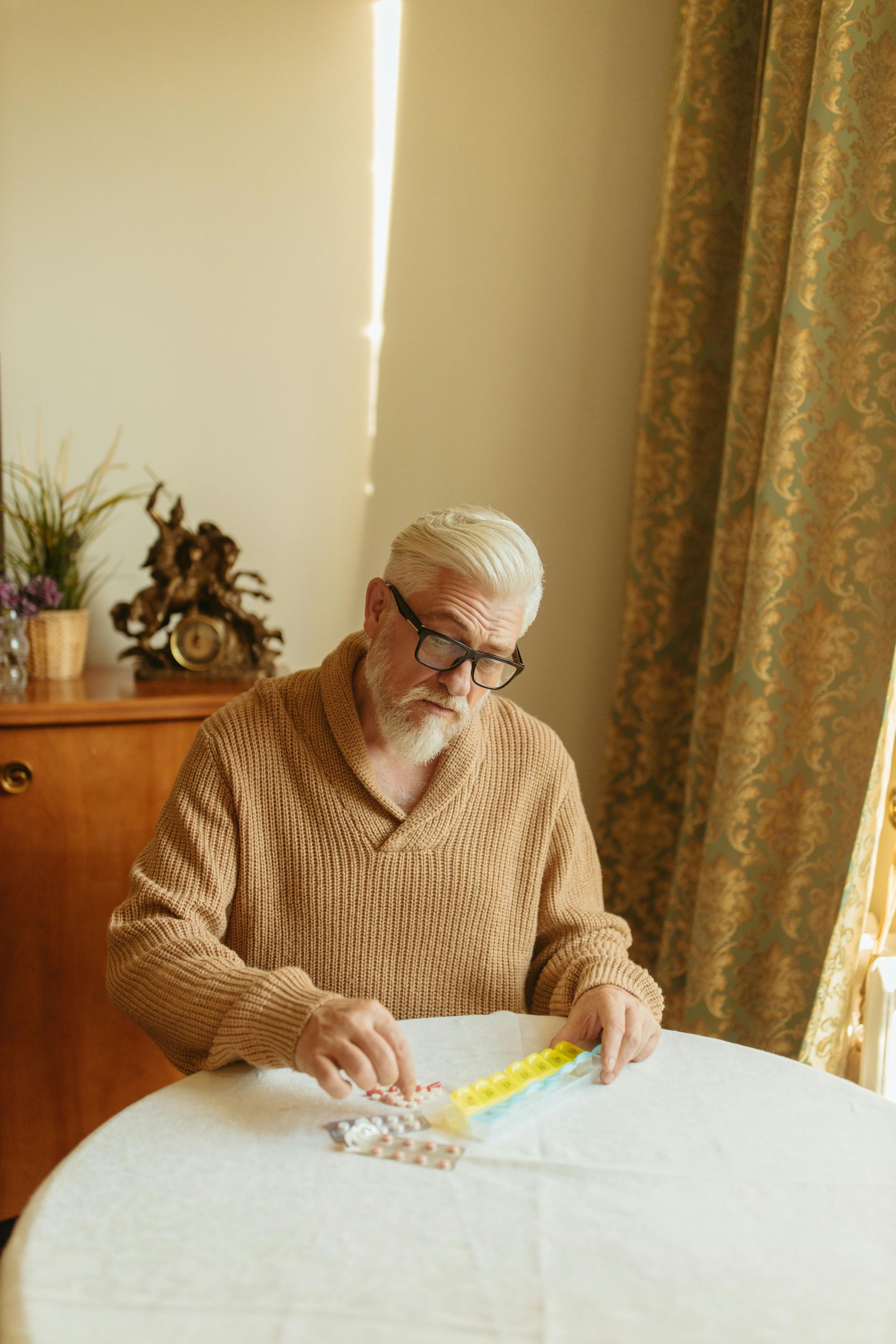 Person seated at a table measuring fabric with a ruler in a sunlit room