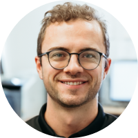 A man wearing glasses and a black shirt is smiling for the camera.