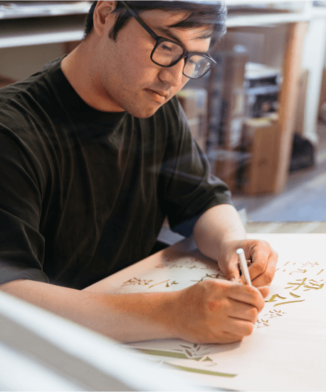 A man wearing glasses is writing on a piece of paper