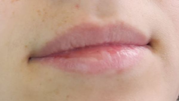 Close-up of human lips, pinkish-red, slightly parted, with visible lip lines, on fair skin.