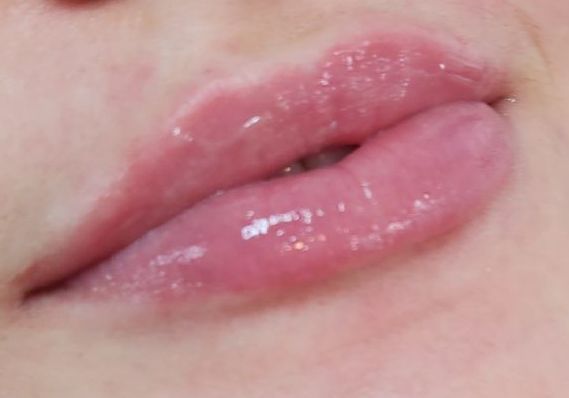 Close-up of glossy pink lips slightly parted.