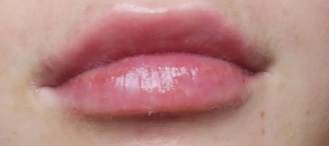 Close-up of a person's slightly parted, full, pink lips.